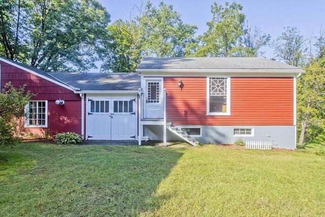 rear view of property featuring a yard, a shingled roof, and entry steps