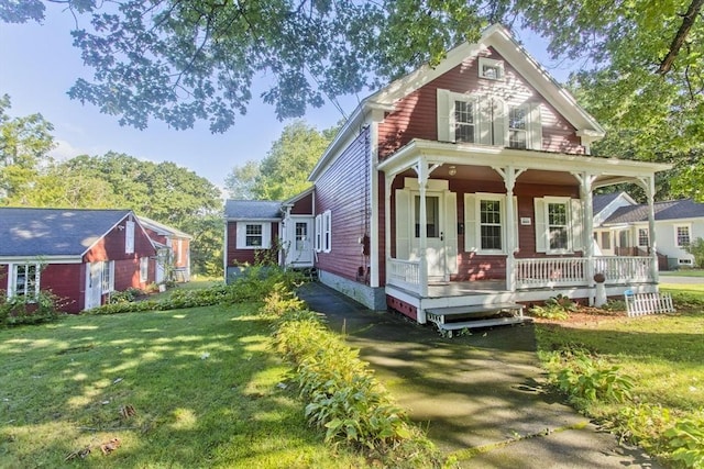 rear view of house with covered porch, crawl space, a yard, and an outbuilding