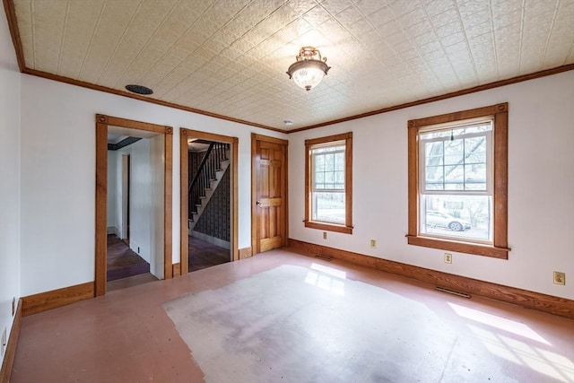 empty room featuring stairway, crown molding, and baseboards