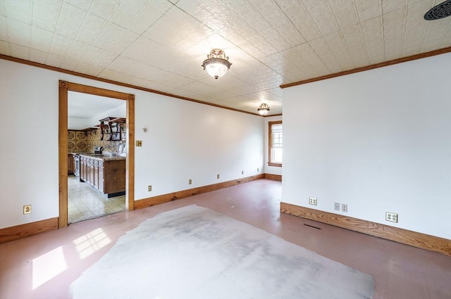 spare room with ornamental molding, concrete floors, and baseboards