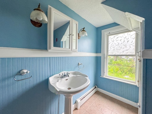 66 Taylor St, Holyoke, MA 01040 - bathroom with baseboard heating, tile patterned flooring, wainscoting, a textured ceiling, and baseboards