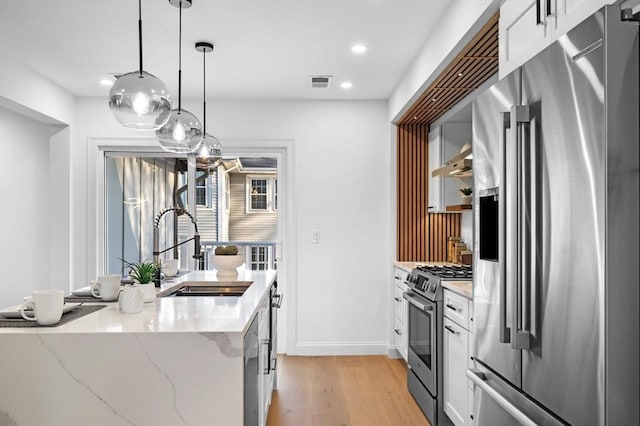 238 Bellevue St Unit 2, Newton, MA 02458 - kitchen with stainless steel appliances, a sink, light wood-type flooring, white cabinets, and recessed lighting