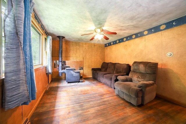 213 Nashua Rd, Billerica, MA 01862 - living area with a wood stove, hardwood / wood-style flooring, a ceiling fan, and brick wall