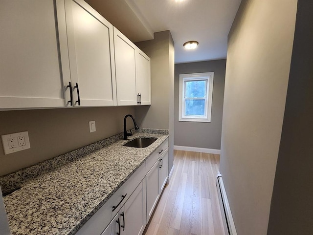 97-99 Blaisdell St Unit 1, Haverhill, MA 01832 - kitchen with a sink, light stone countertops, light wood-style flooring, a baseboard heating unit, and white cabinetry