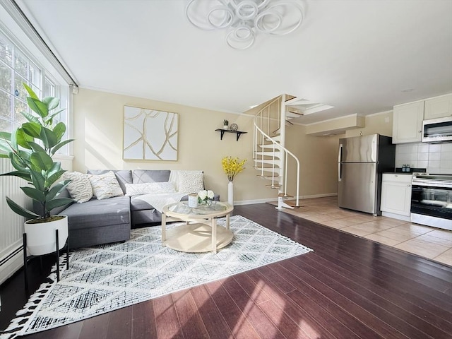 living area featuring stairs, baseboards, and light wood-style floors