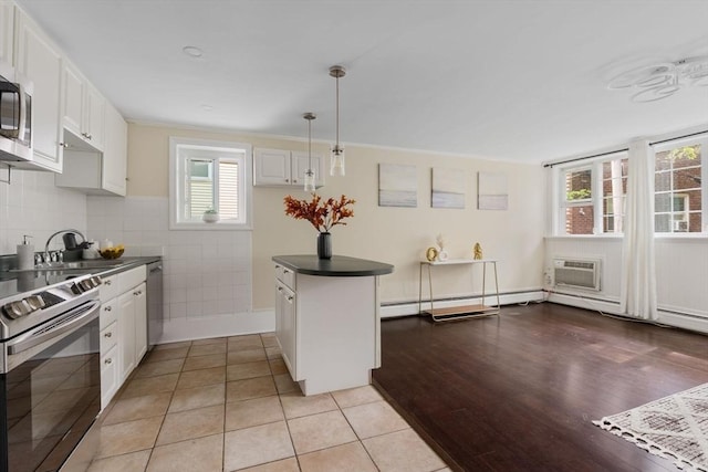 kitchen with white cabinets, dark countertops, a wall mounted air conditioner, baseboard heating, and stainless steel appliances