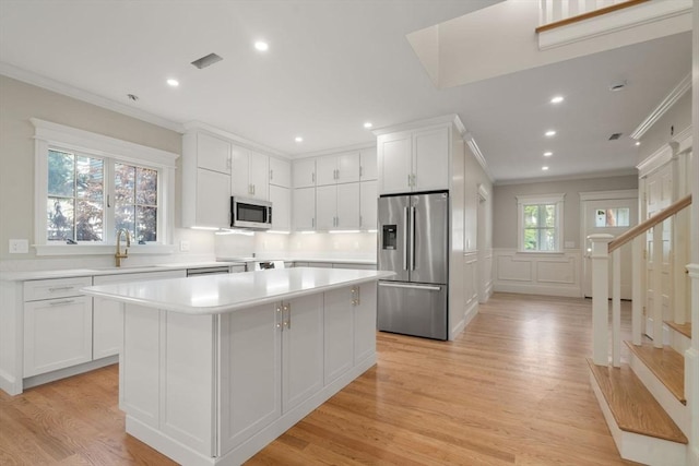 23 Francis Unit 23, Newton, MA 02459 - kitchen with appliances with stainless steel finishes, a sink, ornamental molding, a kitchen island, and light countertops
