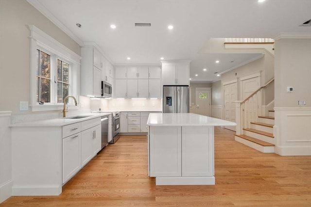 23 Francis Unit 23, Newton, MA 02459 - kitchen with appliances with stainless steel finishes, a sink, a center island, ornamental molding, and white cabinets