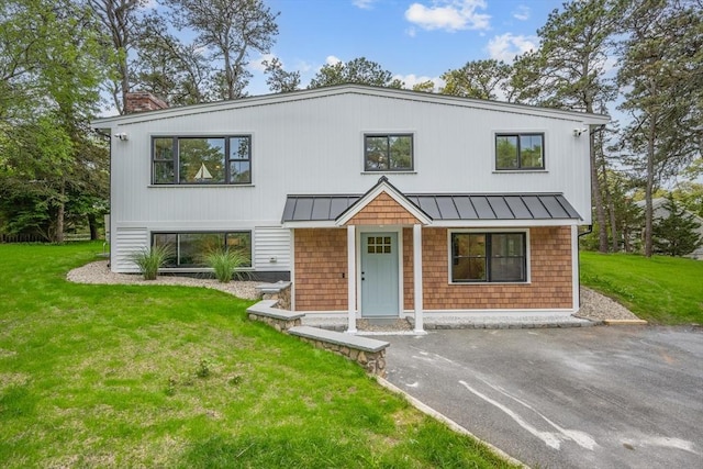 3 Laurie, Harwich, MA 02646 - view of front of home featuring a standing seam roof, a chimney, and a front lawn