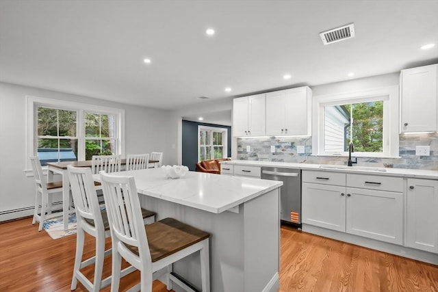 3 Laurie, Harwich, MA 02646 - kitchen featuring stainless steel dishwasher, a sink, light wood finished floors, a kitchen breakfast bar, and decorative backsplash