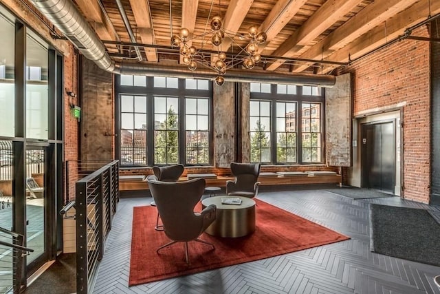 interior space with brick wall, elevator, beam ceiling, and a notable chandelier