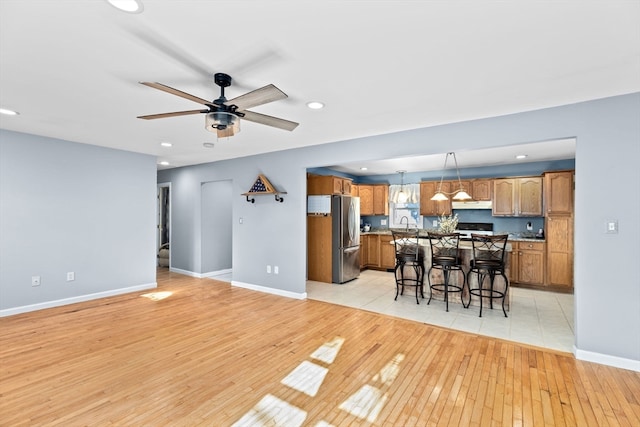 kitchen featuring pendant lighting, a kitchen breakfast bar, stainless steel fridge, light wood-type flooring, and a kitchen island