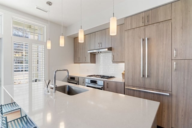 kitchen featuring pendant lighting, sink, appliances with stainless steel finishes, a spacious island, and tasteful backsplash