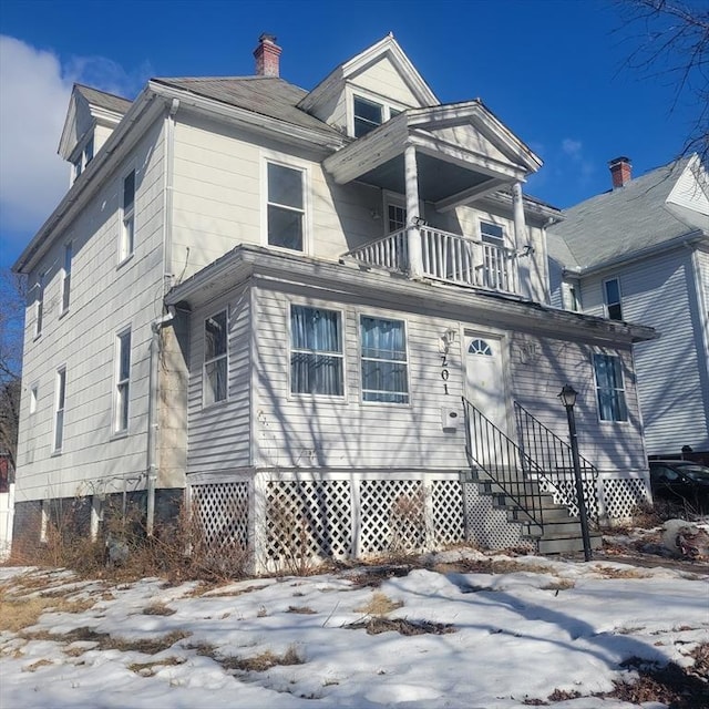 view of front of property featuring a balcony, a chimney, and entry steps