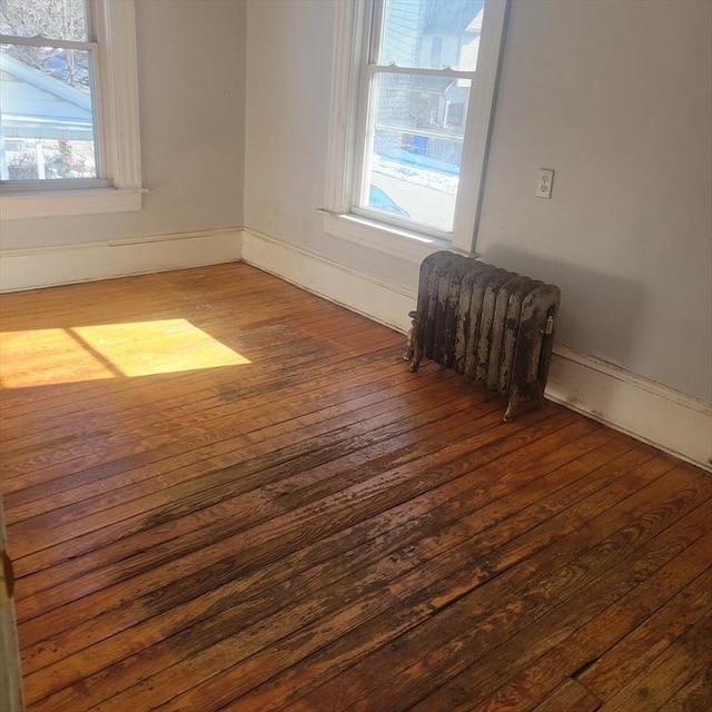 spare room with baseboards, hardwood / wood-style flooring, and radiator