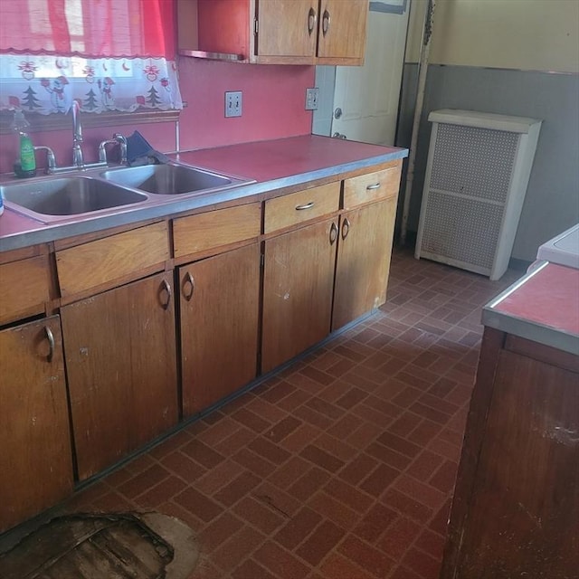 kitchen with brick floor, light countertops, and a sink