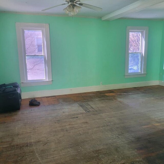 empty room featuring ceiling fan, beamed ceiling, wood finished floors, and baseboards