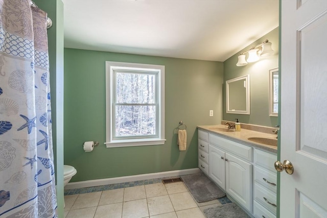 bathroom featuring baseboards, a sink, toilet, double vanity, and tile patterned floors