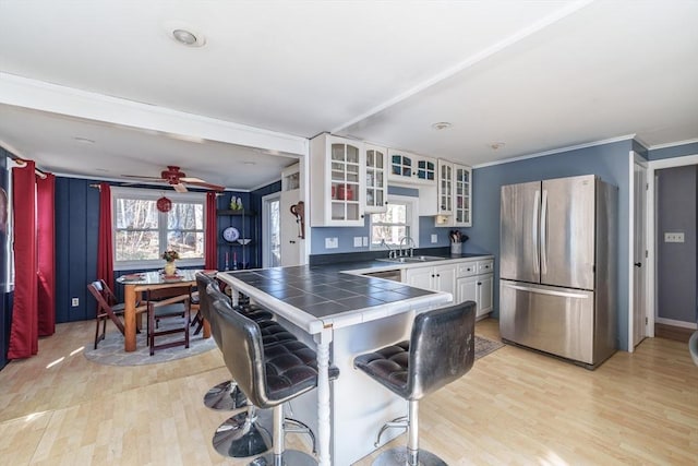 kitchen with light wood-style floors, a wealth of natural light, appliances with stainless steel finishes, a sink, and tile counters