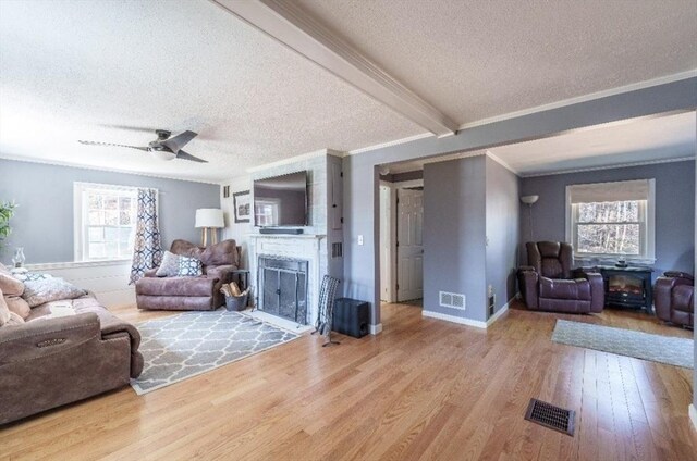 living room featuring visible vents, a fireplace, wood finished floors, and a textured ceiling