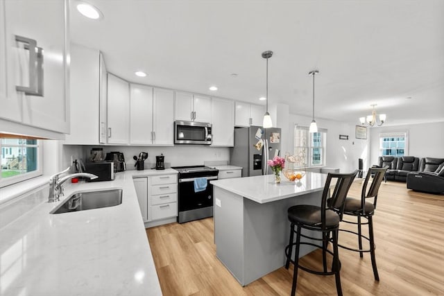 kitchen with white cabinetry, sink, decorative light fixtures, and stainless steel appliances