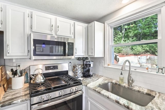 23 Jasmine Ct, Dracut, MA 01826 - kitchen with appliances with stainless steel finishes, a sink, white cabinetry, tasteful backsplash, and a textured ceiling