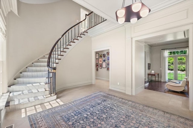 stairs with a towering ceiling, tile patterned floors, and ornamental molding