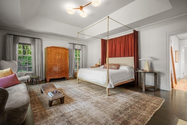 bedroom with dark wood-type flooring, ornamental molding, and a tray ceiling