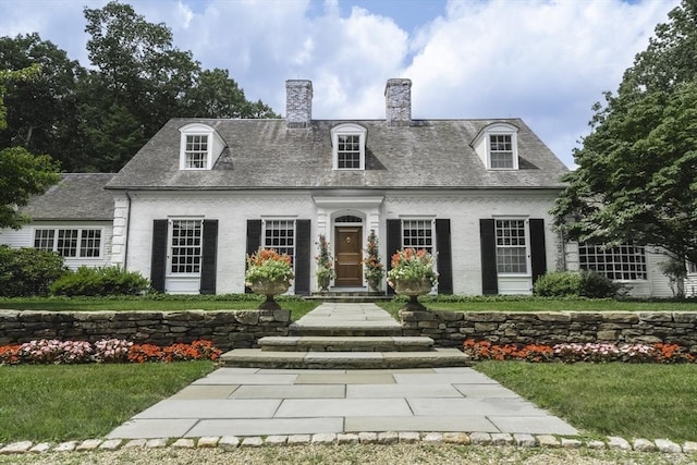 cape cod house featuring a front yard