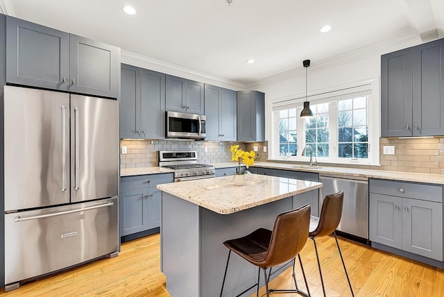 kitchen featuring light hardwood / wood-style flooring, high end appliances, light stone counters, a kitchen island, and decorative light fixtures