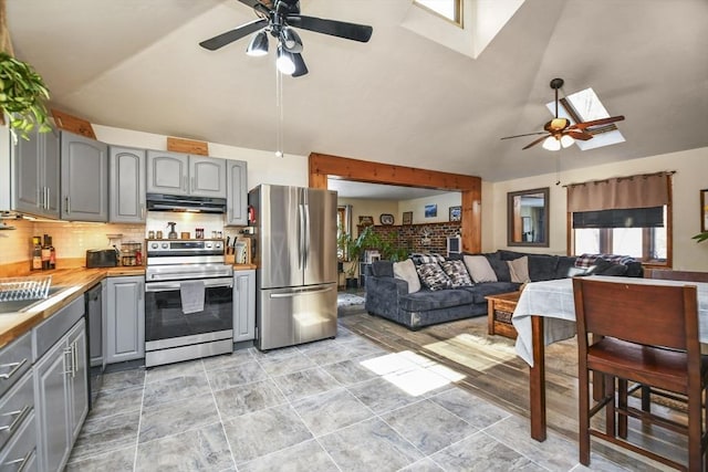 kitchen with ceiling fan, gray cabinetry, lofted ceiling with skylight, backsplash, and stainless steel appliances