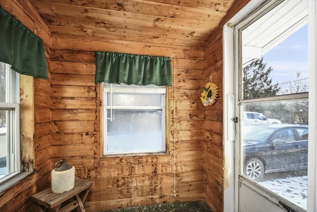 doorway with wood walls, vaulted ceiling, and wooden ceiling