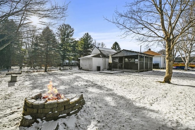 exterior space with a sunroom and an outdoor fire pit