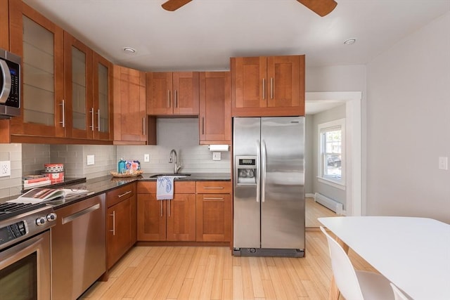 kitchen with ceiling fan, decorative backsplash, appliances with stainless steel finishes, dark countertops, and a sink
