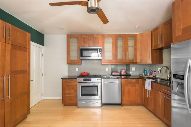 kitchen featuring light wood-type flooring, ceiling fan, brown cabinets, and stainless steel appliances