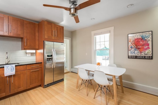 kitchen with light wood-type flooring, a sink, brown cabinets, and stainless steel fridge with ice dispenser