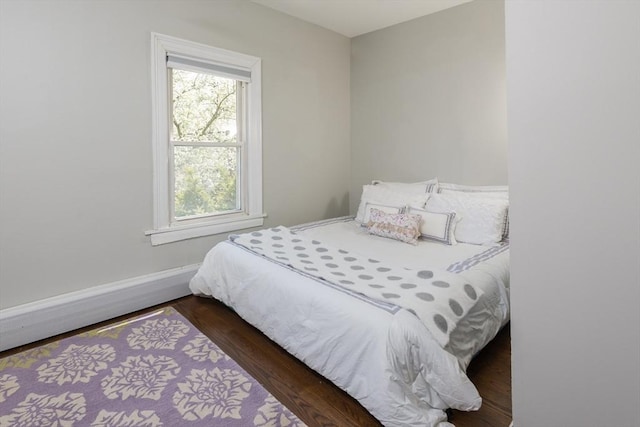 bedroom with baseboards, multiple windows, and wood finished floors