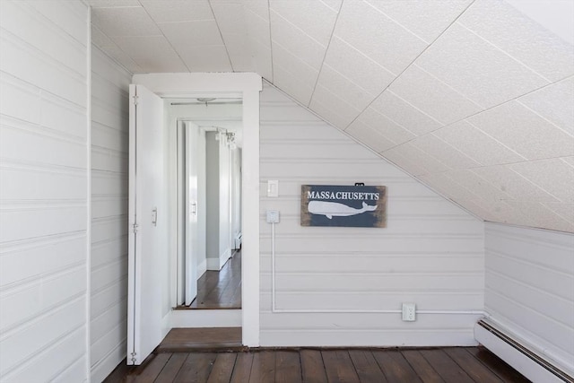 bonus room with wooden walls, a baseboard radiator, and dark wood-style floors