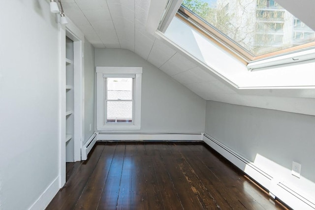 bonus room featuring a baseboard heating unit, built in shelves, lofted ceiling with skylight, and dark wood-type flooring