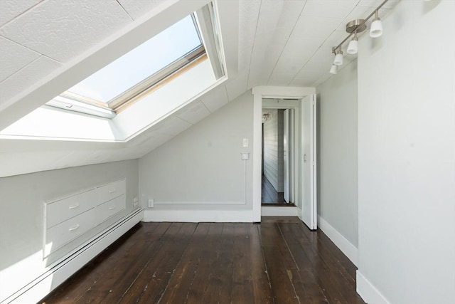 additional living space with baseboards, hardwood / wood-style floors, vaulted ceiling with skylight, and a baseboard radiator