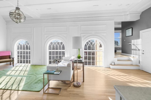 living room with a notable chandelier, crown molding, and light hardwood / wood-style flooring