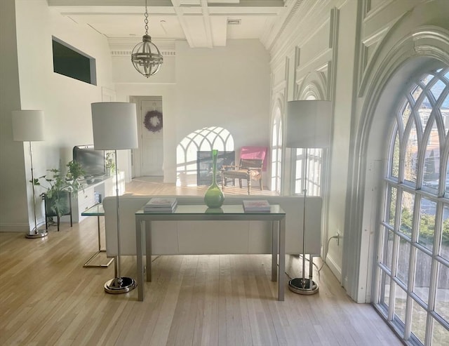 dining area with a notable chandelier, beamed ceiling, coffered ceiling, and light hardwood / wood-style flooring