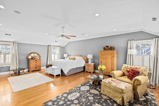 bedroom with vaulted ceiling, wood finished floors, and multiple windows
