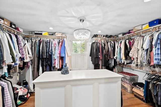 walk in closet with light wood-style flooring and an inviting chandelier