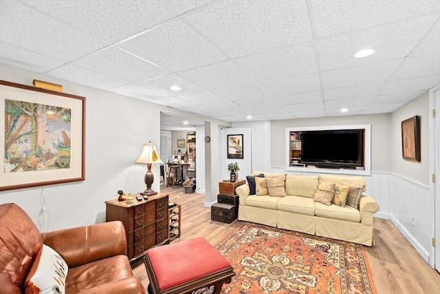living area with wainscoting, wood finished floors, a drop ceiling, and recessed lighting