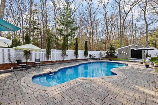 view of swimming pool with an outdoor structure, a fenced in pool, a fenced backyard, and a patio