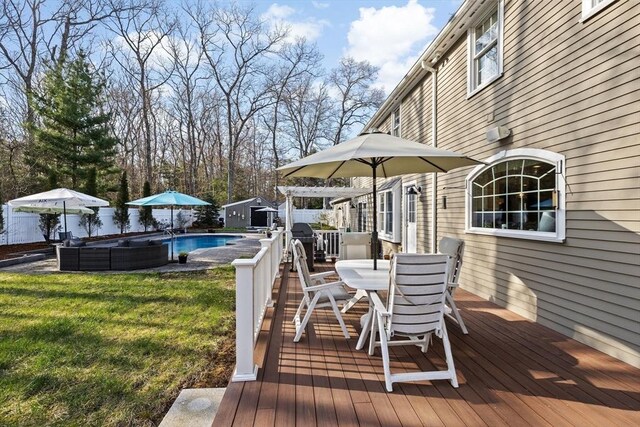 wooden terrace with a fenced in pool, a storage shed, a yard, outdoor dining space, and an outdoor structure