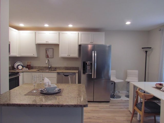 kitchen with sink, light stone countertops, white cabinets, and appliances with stainless steel finishes