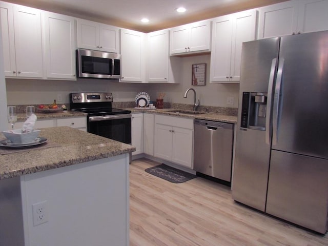 kitchen featuring sink, light stone counters, light wood-type flooring, appliances with stainless steel finishes, and white cabinets