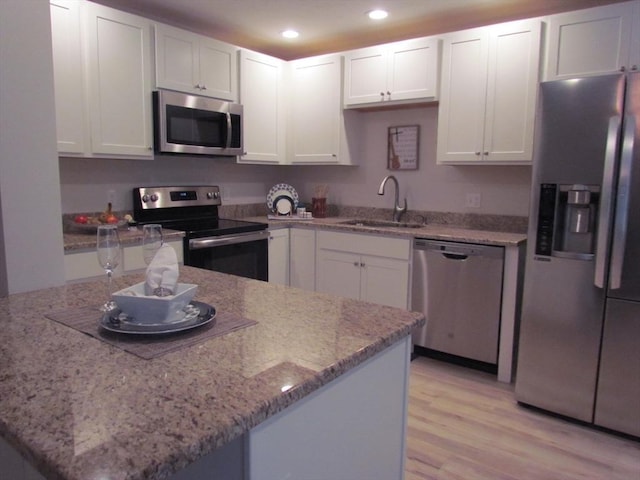 kitchen featuring sink, kitchen peninsula, white cabinets, and appliances with stainless steel finishes